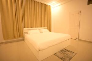 a white bedroom with a white bed and a window at White Lotus Homestay in Dibrugarh