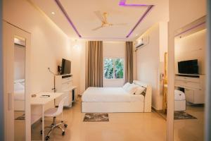 a bedroom with a bed and a desk and a tv at White Lotus Homestay in Dibrugarh