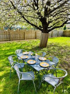 a table with chairs and plates on it under a tree at Très joli logement in Anould
