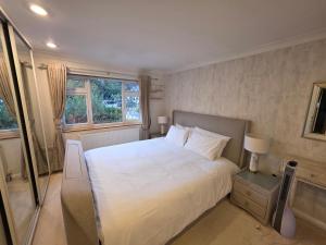 a bedroom with a large white bed and a window at Elegant 5BDR Executive Home Chigwell in Chigwell