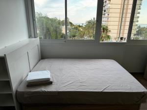 a bed sitting in a room with two windows at Studio 200 m from the sea in Aguadulce +3 photos