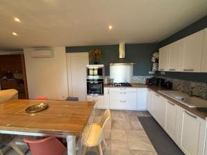 a kitchen with white cabinets and a wooden table at Maison au calme in Chassors