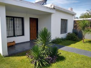 a white house with palm trees in the yard at Hospedaje El Ciruelo in Alta Gracia
