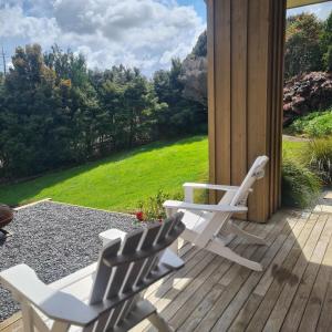 two white lawn chairs sitting on a porch at Sandspit Hideaway in Sandspit
