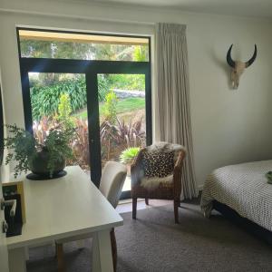a bedroom with a bed and a sliding glass door at Sandspit Hideaway in Sandspit