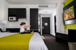 a little girl sitting on a bed in a hotel room at Holiday Inn Express & Suites Puebla Angelopolis by IHG in Puebla