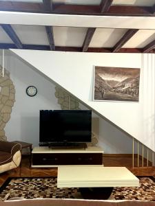 a living room with a tv and a staircase at Serana Stays in Peje