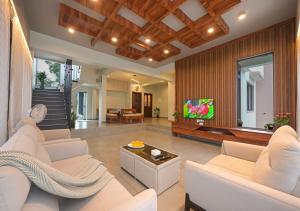 a living room with white furniture and a flat screen tv at 5BHK Villa With Pool & Theater Room in Malavli