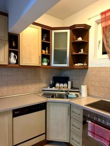 a kitchen with wooden cabinets and a sink at Serana Stays Classic Apartment with Private Bathroom, Free WiFi & Parking, Central Pejë in Peje +20 photos