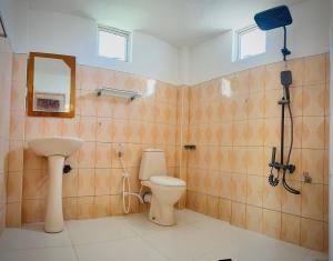Un baño con inodoro, lavabo y espejo. en Wanamal Lake Front Yala, en Tissamaharama