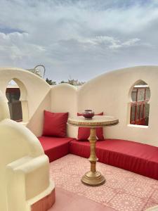 a balcony with red cushions and a table with a bowl on it at Riad Tasneem in Marrakesh