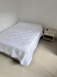 un letto con piumone bianco e tavolino di Casa central con parqueadero ad Armenia