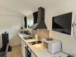 a kitchen with a microwave and a tv on the wall at 4 star holiday home in Löddeköpinge in Löddeköpinge