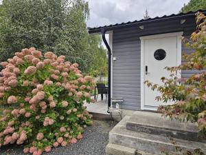a house with a white door and a bush with pink flowers at 4 person holiday home in LÖDDEKÖPINGE in Löddeköpinge +40 photos