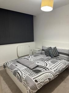 a bedroom with a black and white bed with pillows at Elegant 1 Bed Flat Near Stadium & Shops and free parking in Manchester