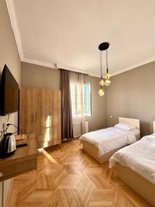 a bedroom with two beds and a desk and a television at Nest Stay in Tbilisi City