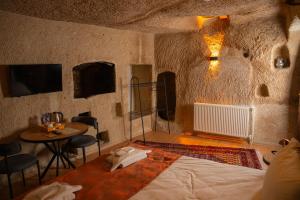 a bedroom with a bed and a table in a cave at Colina Stone House in Mustafakemalpaşa