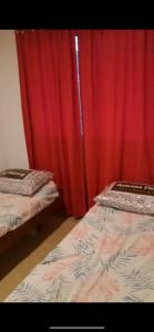 2 camas en una habitación con cortina roja en cabaña de montaña, en La Estancia