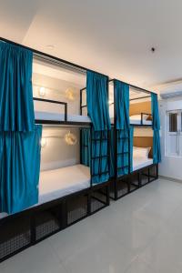 een kamer met 3 stapelbedden en blauwe gordijnen bij SAIR Hostel, Varanasi - 100m from Assi Ghat in Varanasi