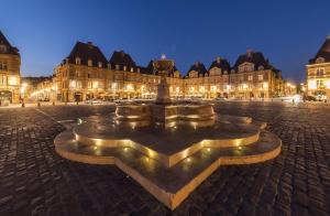 una fuente frente a un edificio por la noche en Appartement Chic - Parking Prive, en Charleville-Mézières