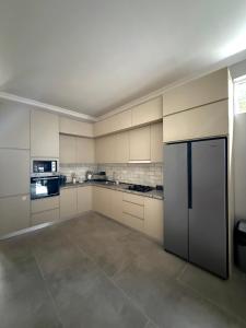 a large kitchen with white cabinets and a refrigerator at Nest Stay in Tbilisi City
