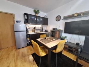 a kitchen with a table with yellow chairs and a television at ТРИ ПЛАНИНИ ап113 in Razlog