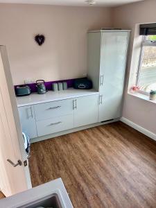 a white cabinet in a room with a wooden floor at Denzels Den Apartment 2 in Llandudno Junction +9 photos