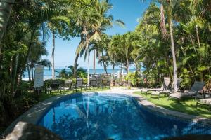 プラヤ・エルモサにあるOla Bonita BeachFront Apart Hotelのヤシの木と海のスイミングプール