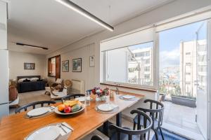 a dining room with a table and chairs and a large window at 2BR Apt, Port View, Balcony, Walk to Ferry in Piraeus