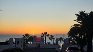 a sunset over a parking lot with a rul sign and palm trees at New Balcon Amadores Best Teide View Apartment Puerto Rico in Mogán +6 photos