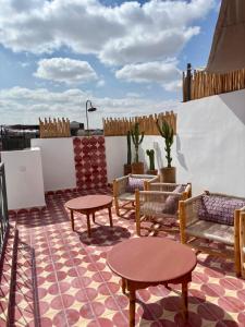 a patio with tables and chairs on a roof at Riad MONA Marrakech Kasbah Médina in Marrakech