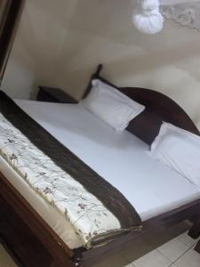a bed with a wooden frame and white sheets and pillows at POWERNET SERVICES Ltd MOTEL in Kigali