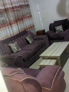 a living room with purple couches and a wooden table at POWERNET SERVICES Ltd MOTEL in Kigali