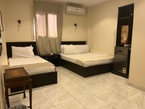 a bedroom with two beds and a table and a window at Ramses Pyramids INN in Cairo