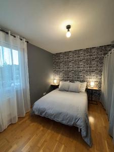 a bedroom with a bed and a brick wall at CNPE Bugey 10 MN - Aéroport LYS 18 MN in Pont-de-Chéruy