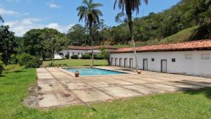 a swimming pool in a yard next to a building at Fazenda Cachoeira Grande in Vassouras
