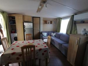 a living room with a table and a blue couch at Mobilhome Vendée Océan in Brem-sur-Mer