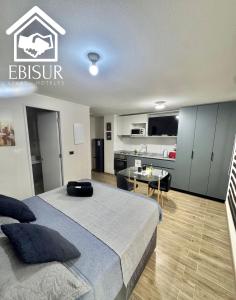 a bedroom with a large bed and a kitchen at EBISUR Apart - Hoteles MAIPU 2 in Concepción