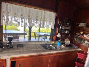 a kitchen with a sink and a table and a window at Cabaña las Bromelia in San Vito
