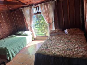 a bedroom with two beds and a large window at Cabaña las Bromelia in San Vito