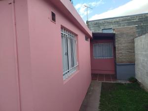 ein rosafarbenes Haus mit einem Fenster an der Seite in der Unterkunft Departamento Manna in Alta Gracia