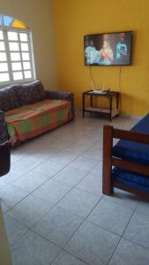 a living room with a couch and a tv on the wall at Perequê Açu beach house in Ubatuba