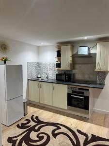 a kitchen with white cabinets and a white refrigerator at A Cosy and Spacious Studio Flat in Navestock