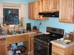 a kitchen with wooden cabinets and a stove top oven at Cook's Place in Tok