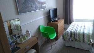 a hotel room with a green chair in a bedroom at Driftwood B&B Weymouth in Weymouth