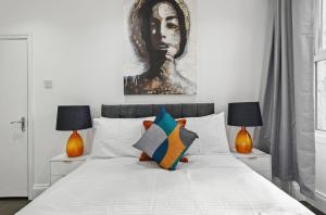 a bedroom with a large white bed with two lamps at Amazing 1 Bedroom Flat in Central London in Moffat