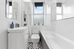 a white bathroom with a toilet and a sink and a tub at Amazing 1 Bedroom Flat in Central London in Moffat
