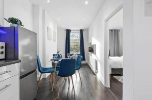 a kitchen and dining room with a table and blue chairs at Amazing 1 Bedroom Flat in Central London in Moffat
