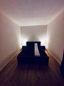 a black bed in a room with two lamps at Modernes City Apartment am See, Zentral in Rorschach