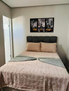 a bed in a bedroom with two pictures on the wall at Residencial Leste Universitário in Goiânia